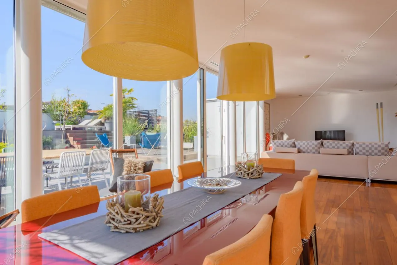 Tavolo da pranzo rosso nella luminosa zona living con pavimento in parquet e vetrate