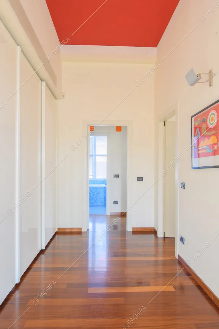 Corridoio con pavimento in parquet, armadi a muro, pareti bianche e soffitto rosso