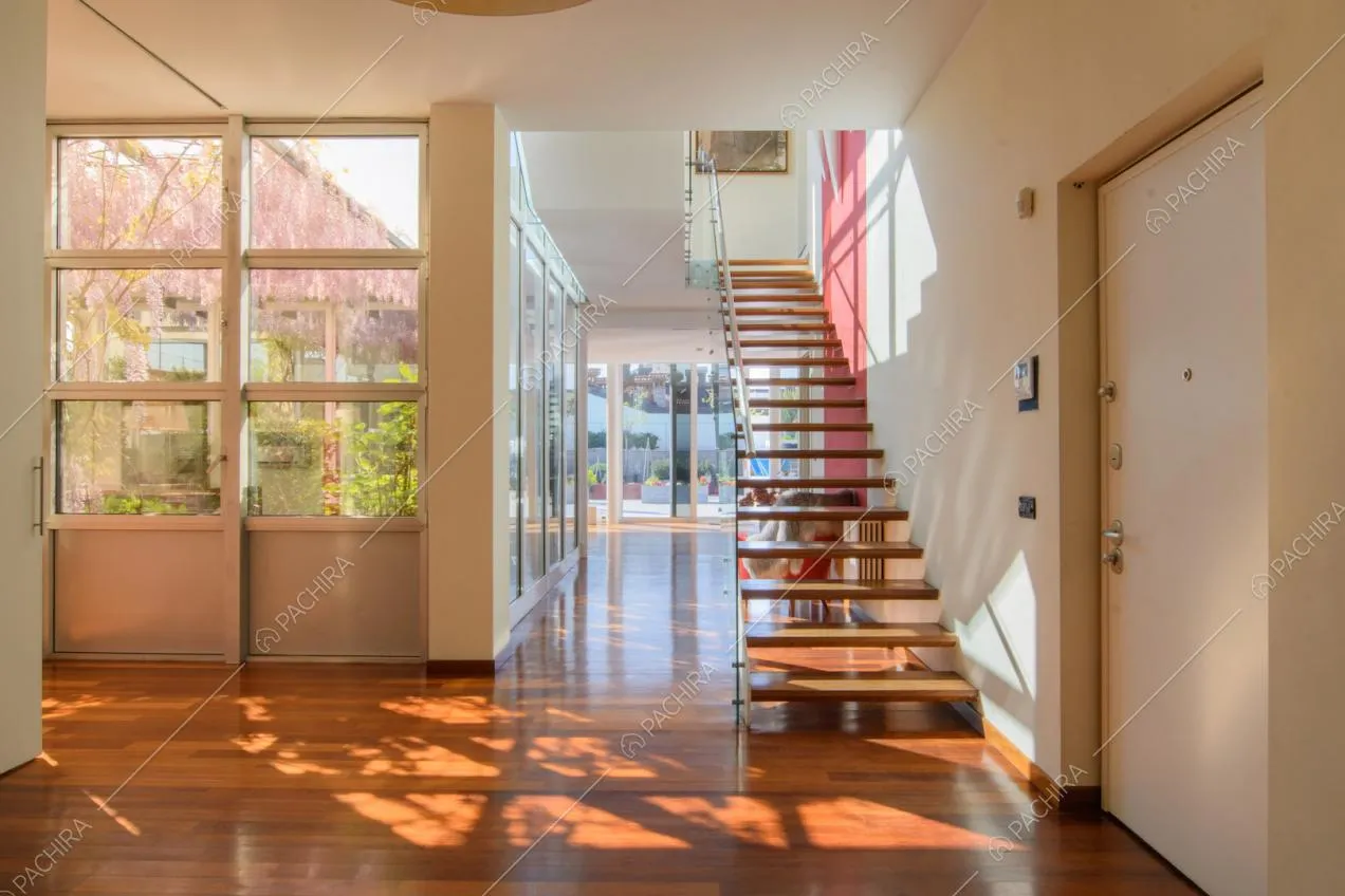 Pavimento in parquet nell'atrio con scale, porte-finestre e vista sulla cucina