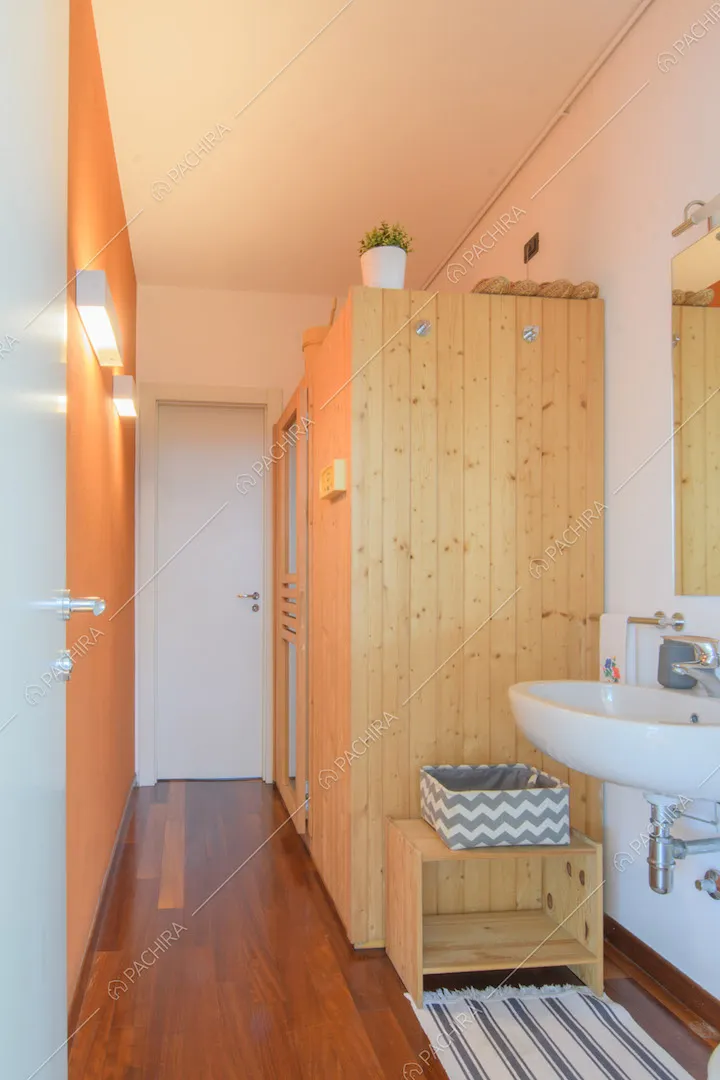 Luminoso bagno con parete arancione e pavimento in parquet