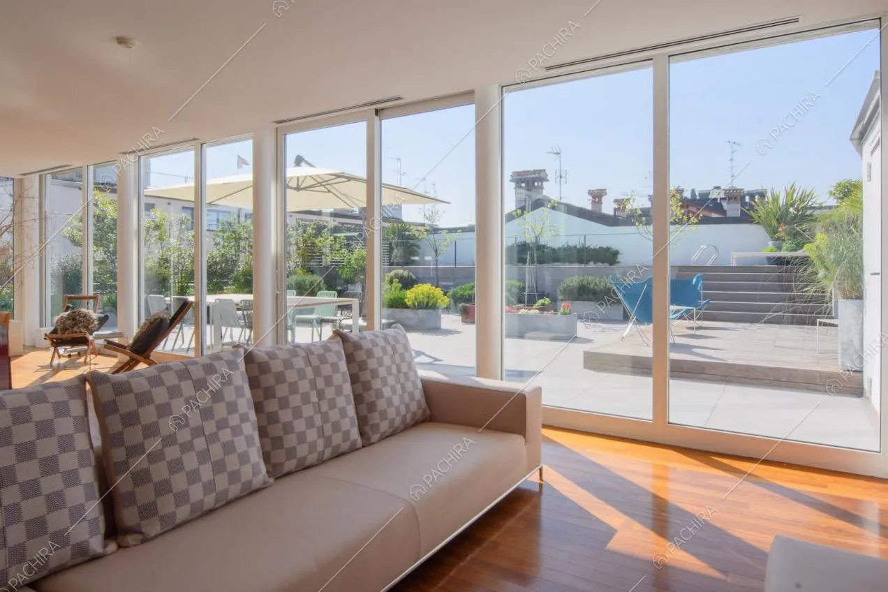 Luminosa zona living con pavimento in parquet, divano beige e vista sulla terrazza