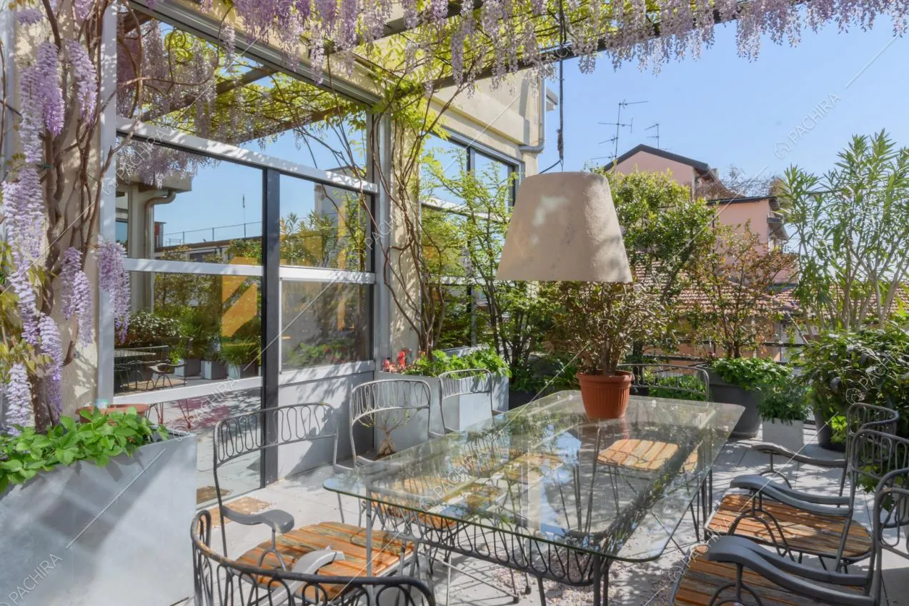 Tavolo da pranzo con piano in vetro sotto la veranda con il glicine