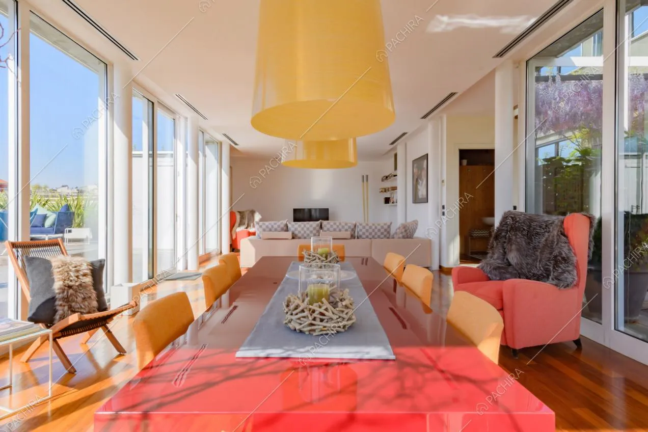Tavolo da pranzo rosso e sedie arancioni nella zona living con pavimento in parquet