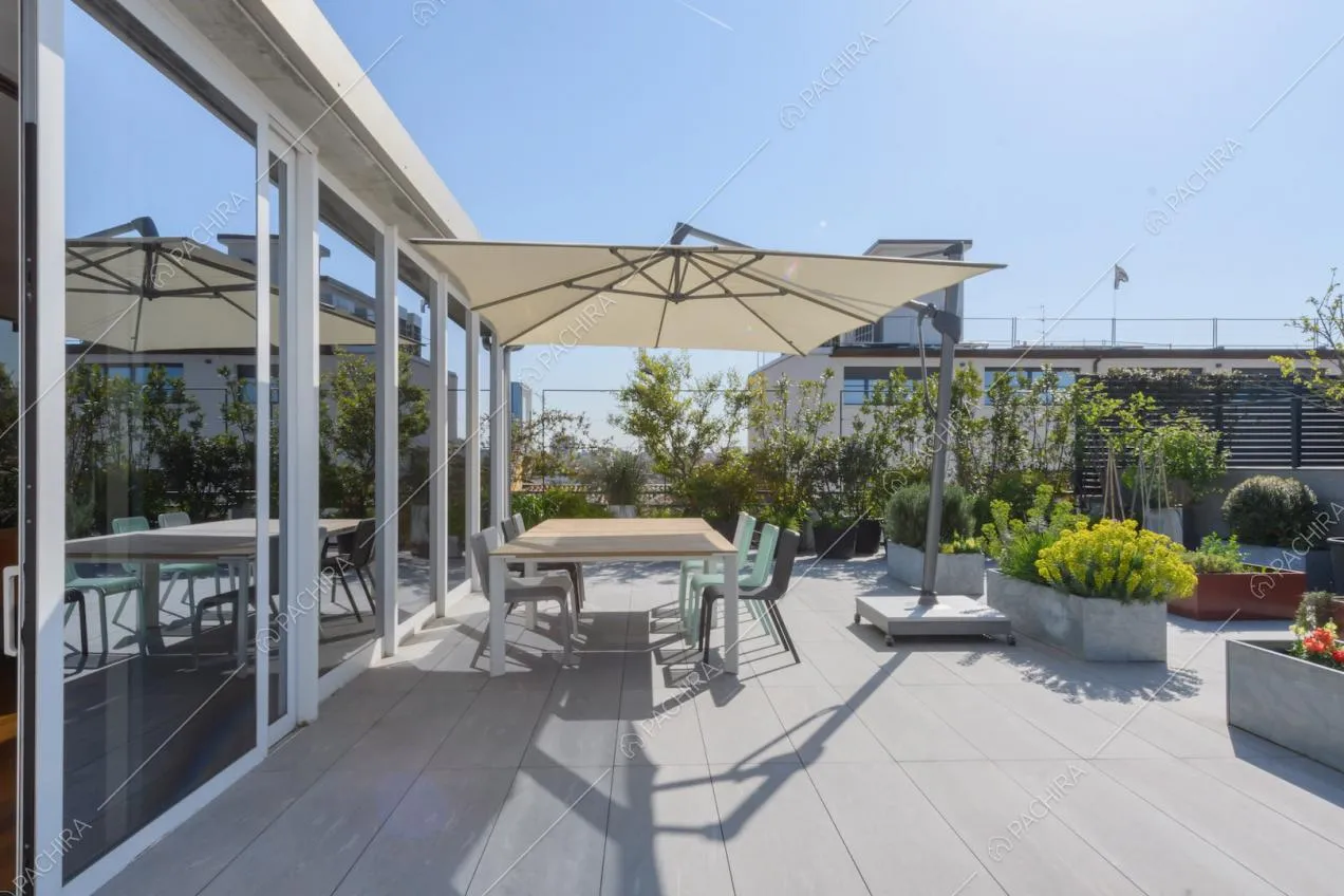 Grande terrazza con tavolo da pranzo, ombrellone e pavimento in lastre grigie