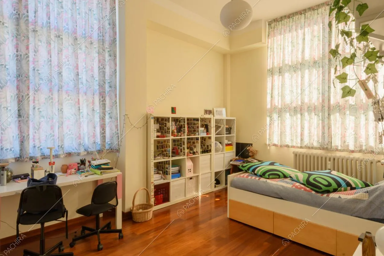 Camera da letto singola con vetrate, pavimento in parquet e scrivania