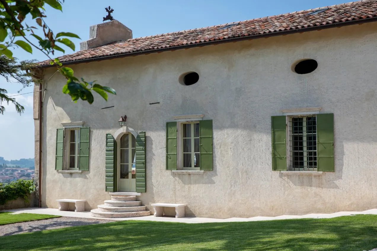 Esterni bianchi della location dalle persiane verdi e piccola scalinata di ingresso