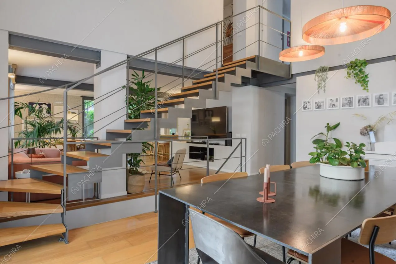 Tavolo da pranzo in metallo nella sala con scale e alto soffitto