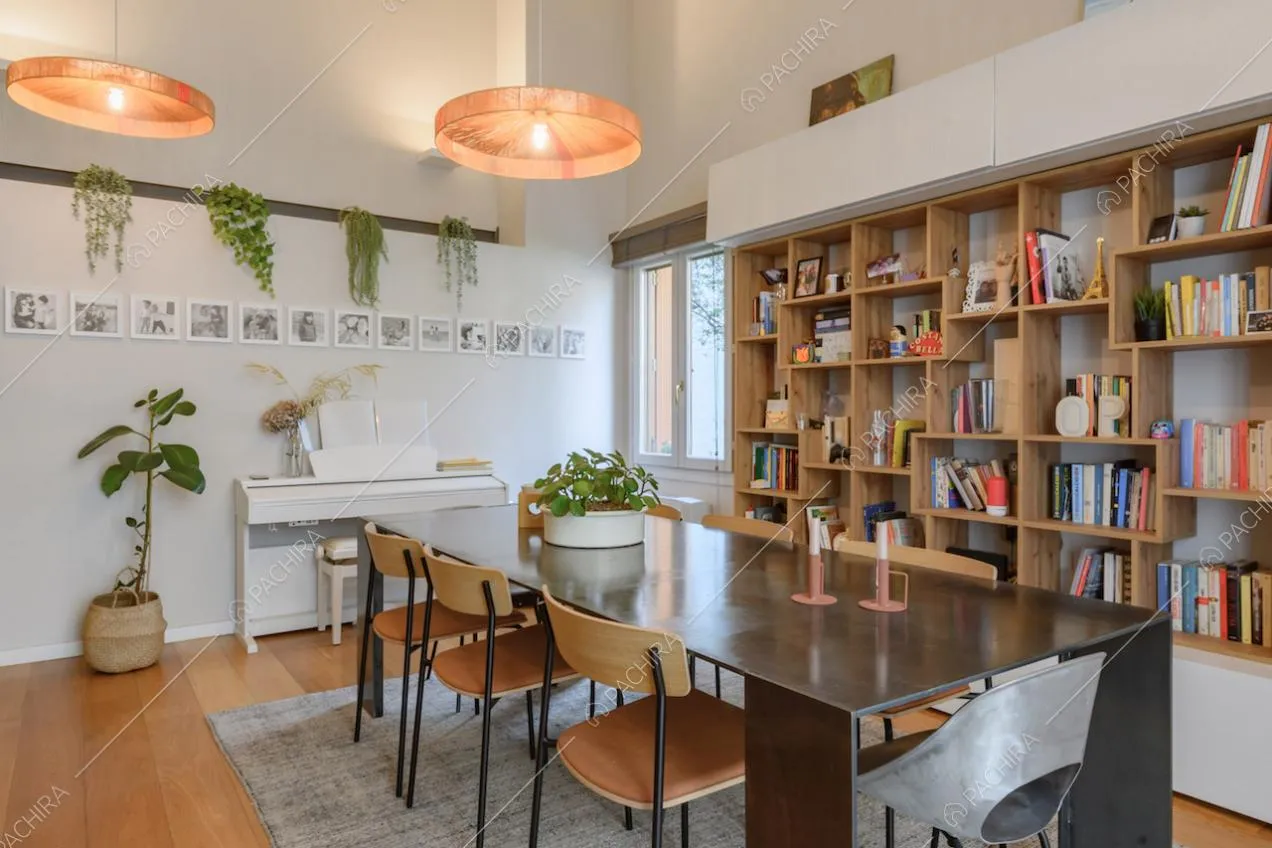 Luminosa sala da pranzo con libreria, pavimento in parquet e lampadari di design