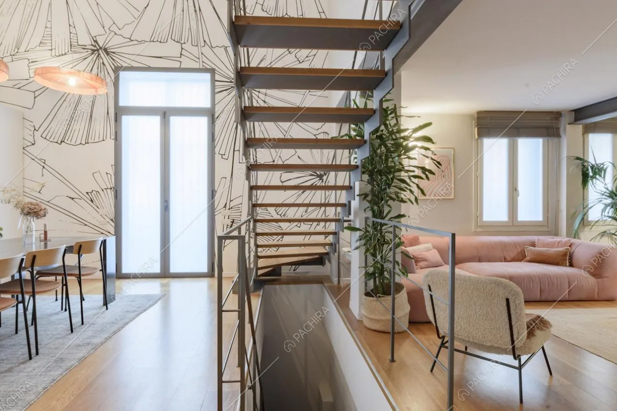 Vano scale nella grande zona living con pavimento in parquet e carta da parati