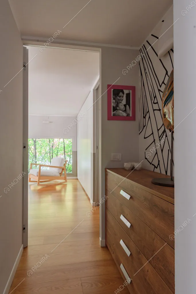 Dal corridoio con mobile in legno e pavimento in parquet vista sulla camera da letto