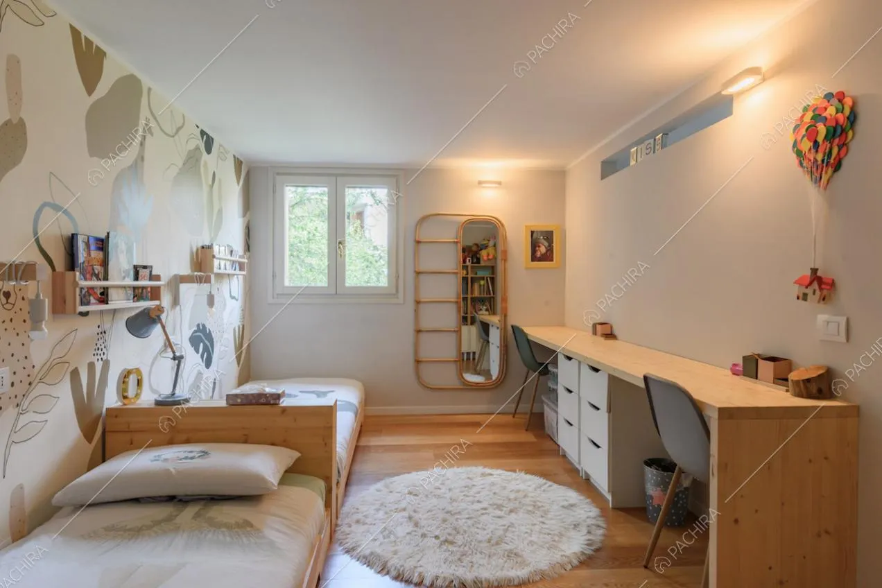 Luminosa camera con carta da parati, due letti singoli e lunga scrivania