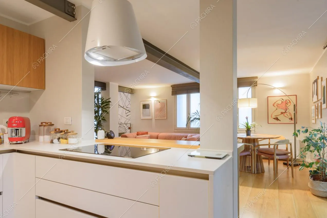Cucina bianca con fornelli a induzione e vista sulla sala con tavolo da pranzo