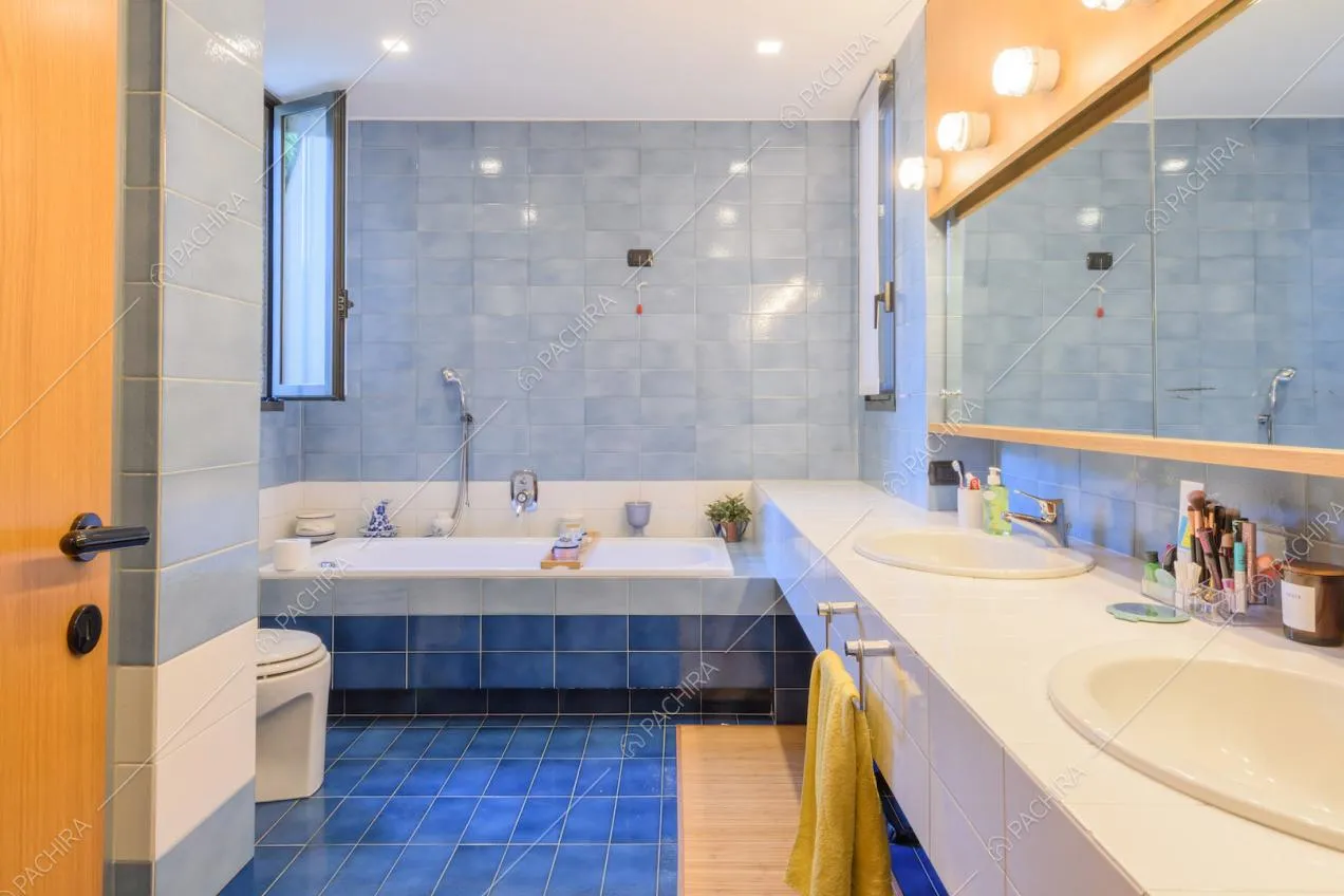 Bagno con piastrelle blu su pavimento e pareti e doppio lavandino