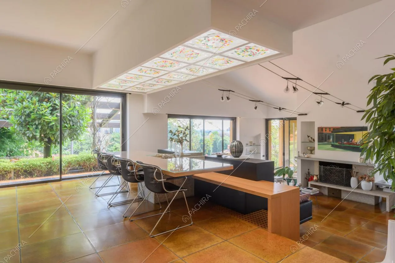 Zona living con pavimento in piastrelle marroni e grandi vetrate