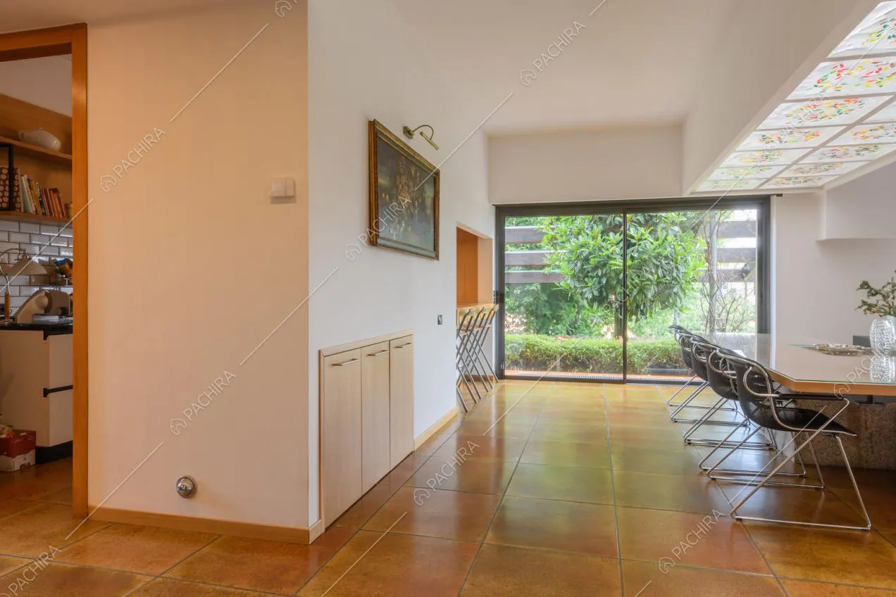 Pavimento in piastrelle marroni nella zona living con pareti bianche e vetrate