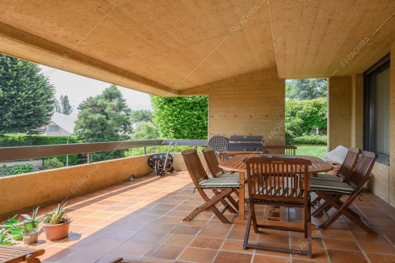 Terrazza coperta con tavolo da pranzo e sedie in legno da esterni
