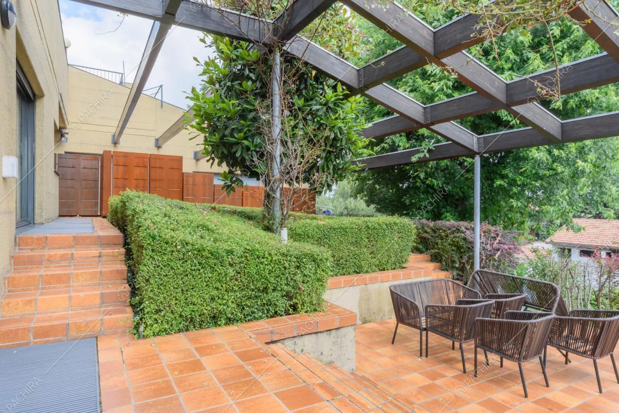 Terrazza con piastrelle marroni, poltrone da esterno e struttura nera
