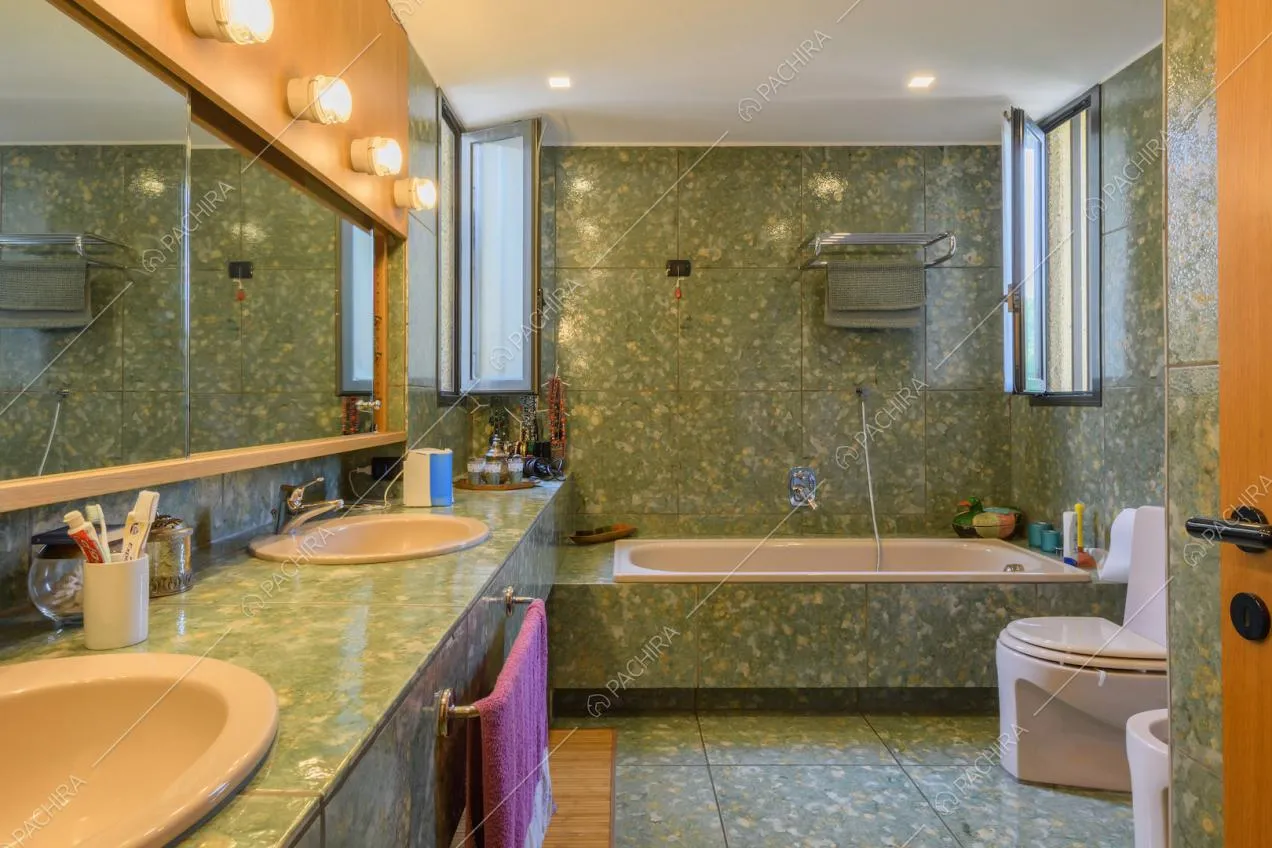Grande bagno con pareti e pavimento in marmo verde e vasca