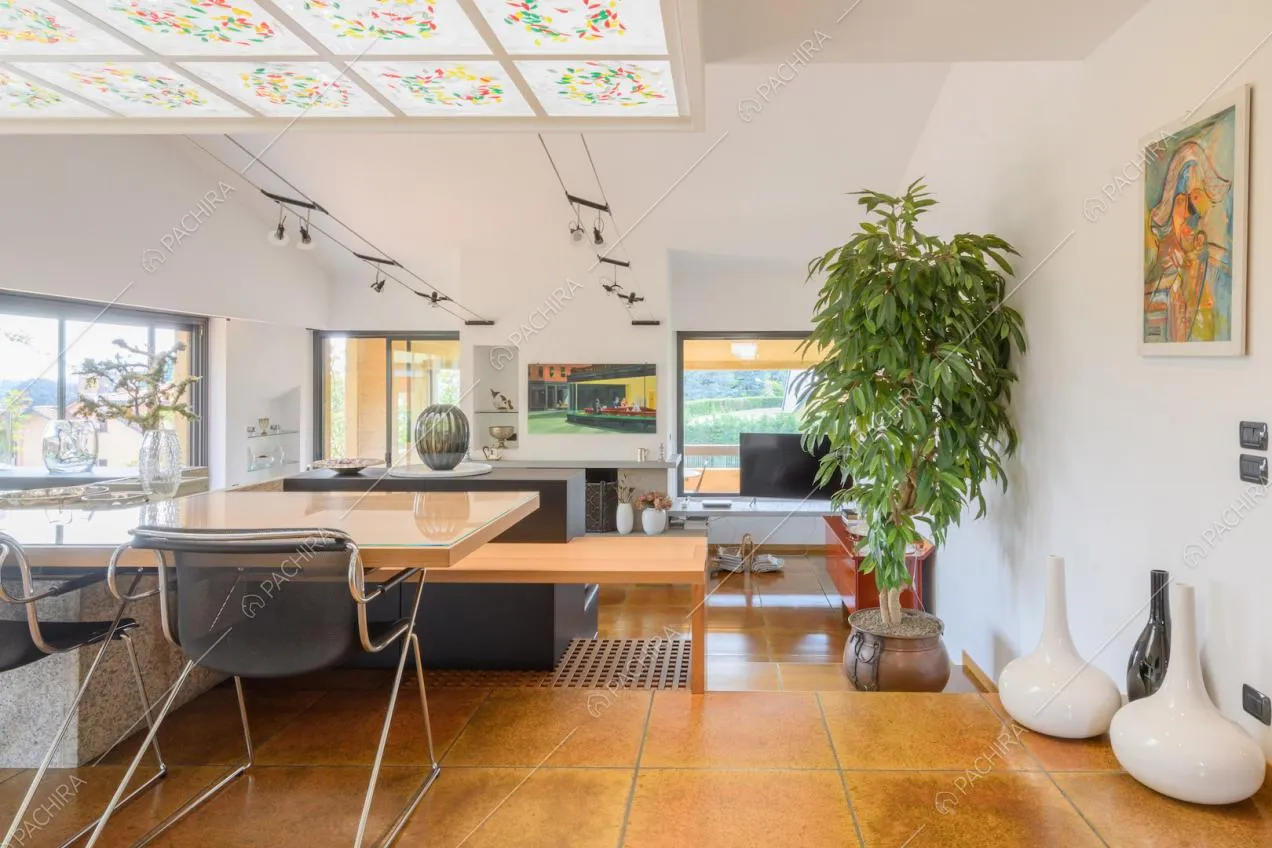 Tavolo da pranzo in legno con sedie di design nella zona living con grandi vetrate