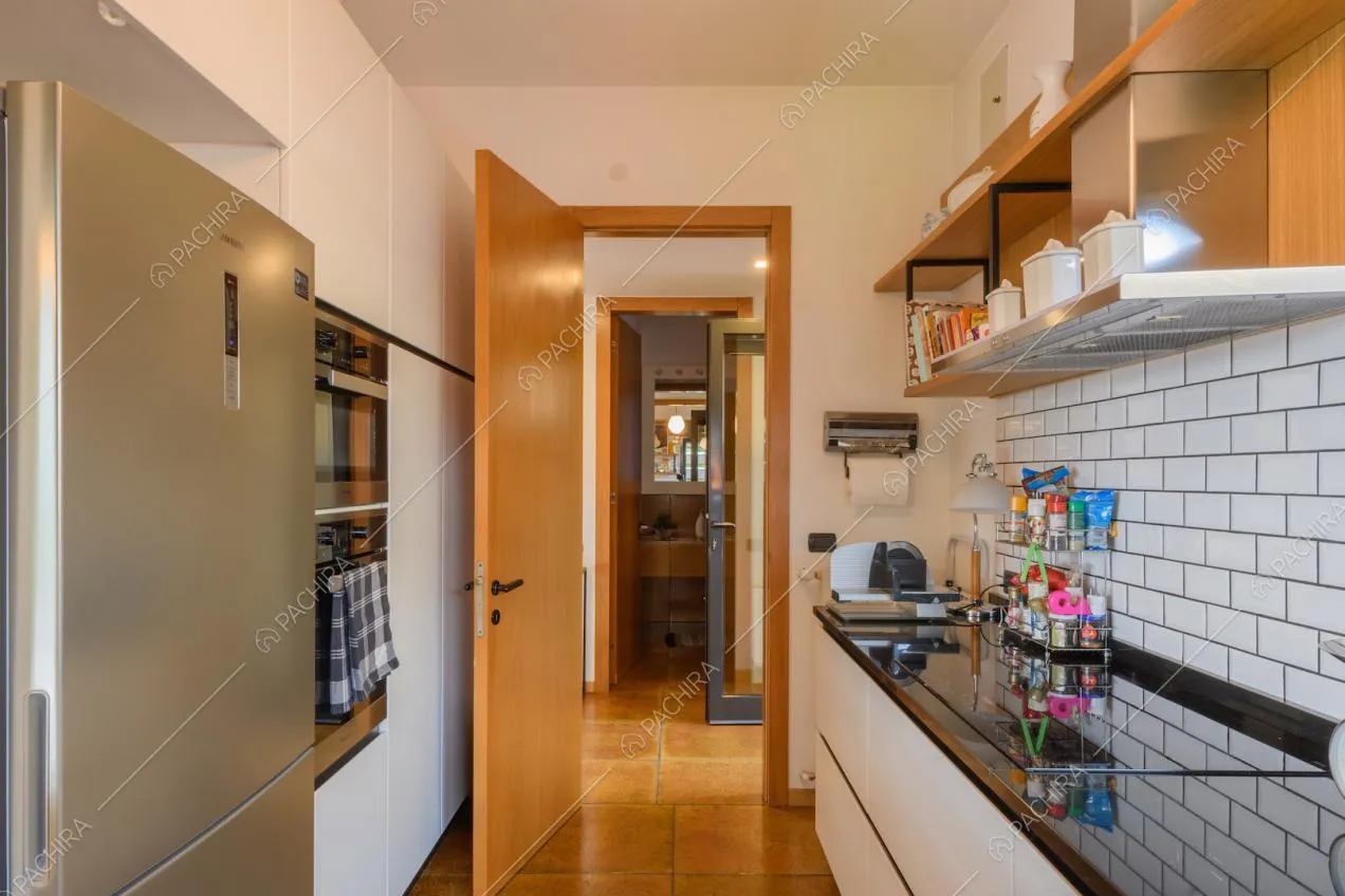 Cucina con fornelli a induzione, parete in piastrelle bianche e vista sul bagno