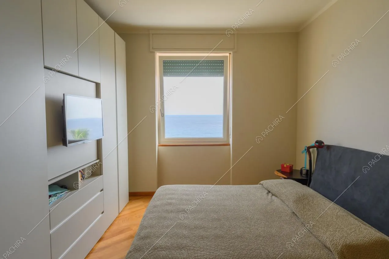 Camera da letto matrimoniale con armadio bianco a muro e vista sul mare