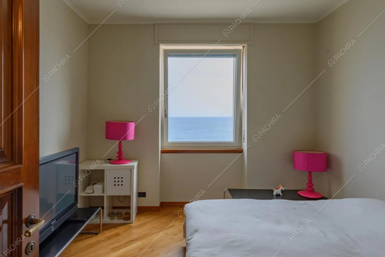 Luminosa camera da letto matrimoniale con pavimento in parquet e vista sul mare