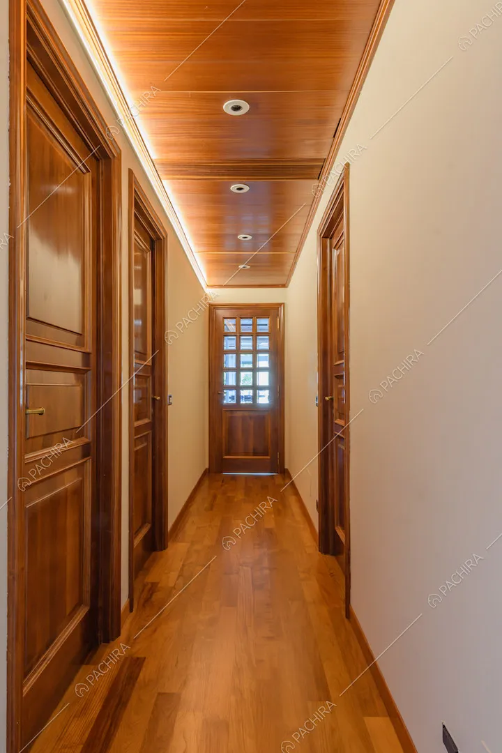 Lungo corridoio con pavimento in parquet e soffitto in legno