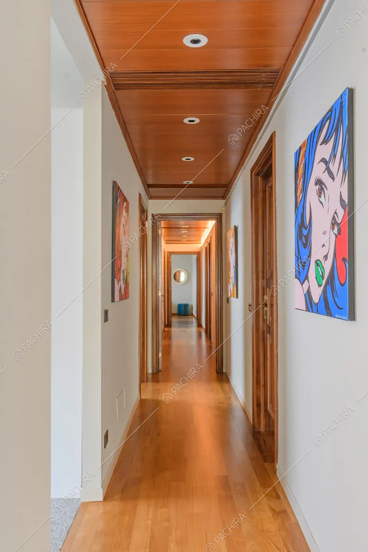 Lungo corridoio con pareti bianche e pavimento in parquet
