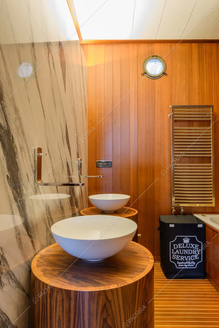 Doppio lavandino nel bagno con pareti in marmo e in legno