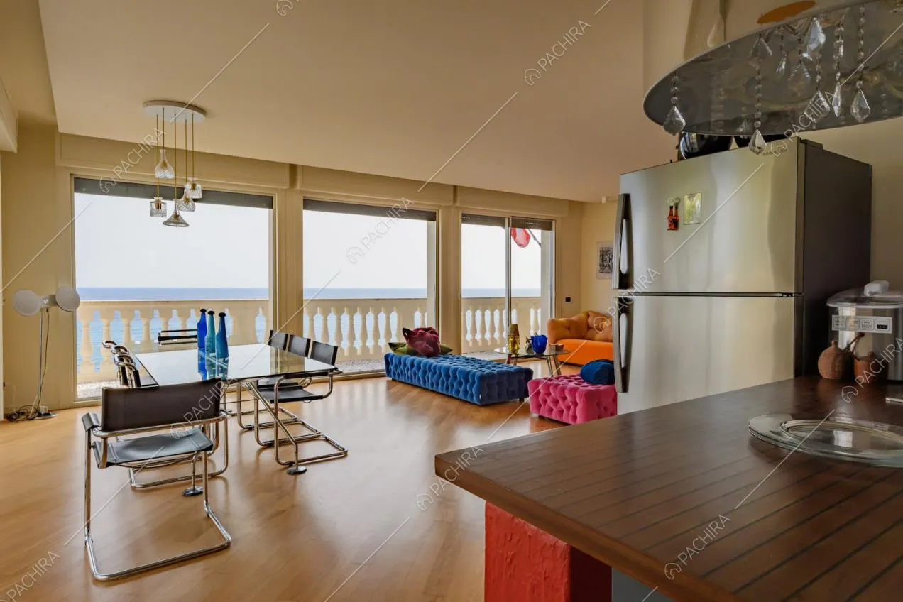 Zona living con pouf colorati, tavolo da pranzo e vetrate
