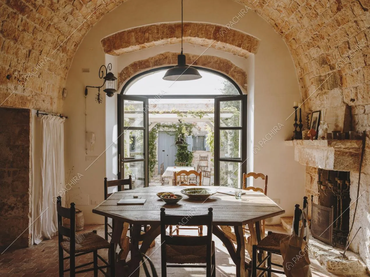 Tavolo da pranzo nella sala con camino illuminata dalla porta-finestra