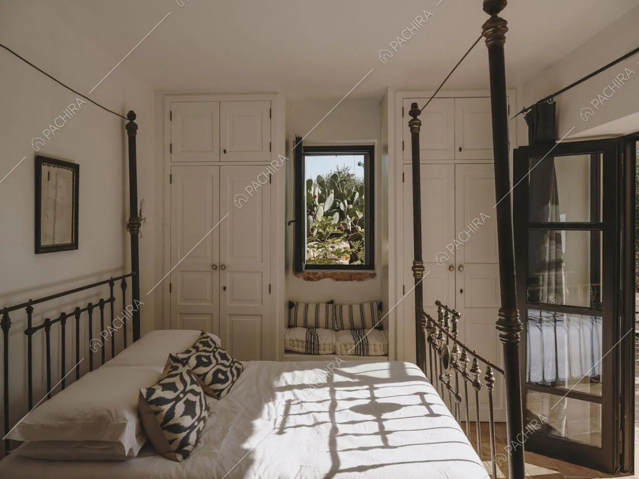 Letto matrimoniale nella camera con pareti bianche e armadi con boiserie