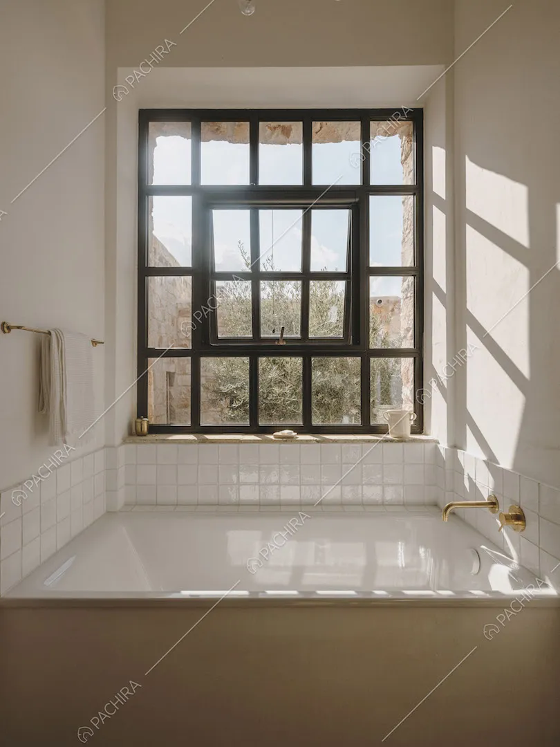 Ampia vasca nel luminoso bagno con pareti bianche e grande vetrata
