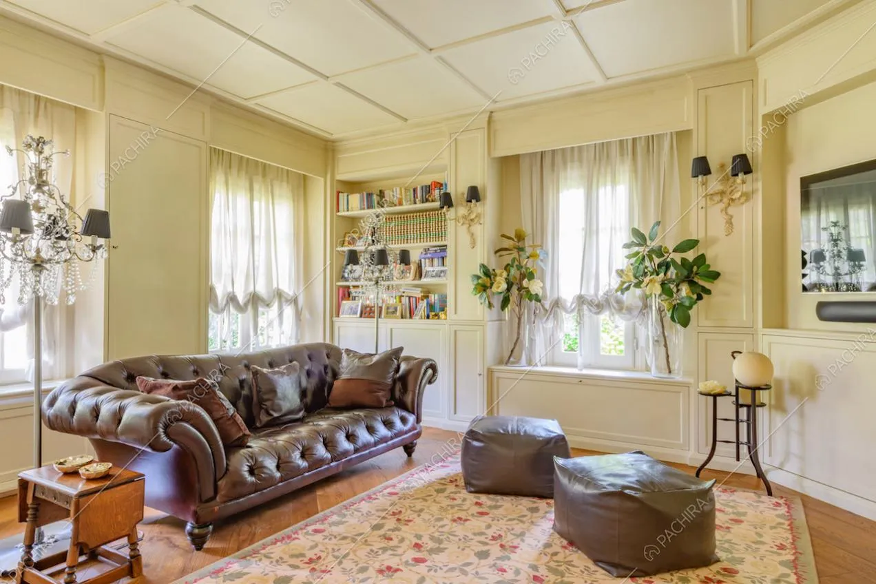 Salotto con boiserie su pareti e soffitto, divano e pouf in pelle