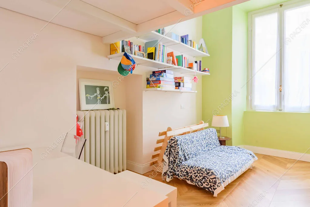 Scrivania e divano letto nella camera con parete verde e pavimento in parquet