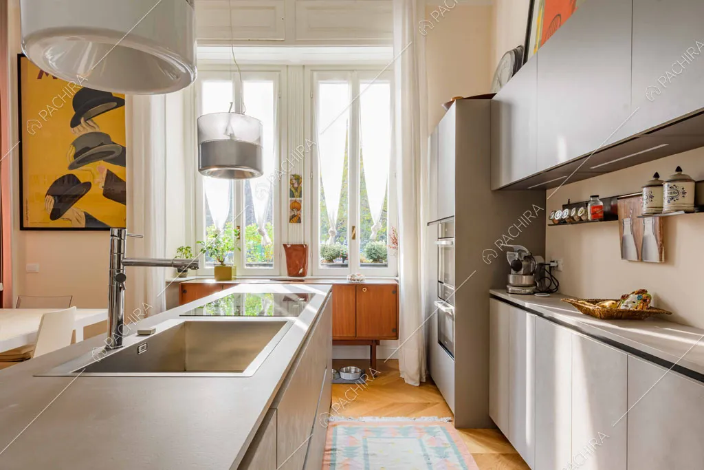 Cucina grigia a isola con fornelli a induzione e pavimento in parquet a spina di pesce