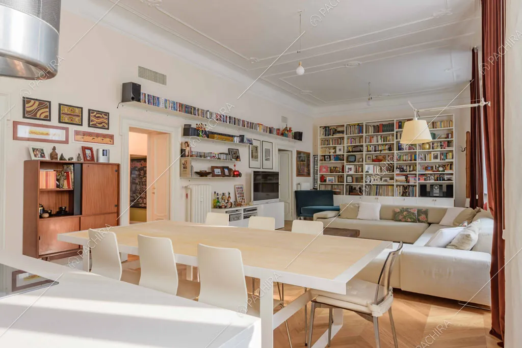 Boiserie sul soffitto della luminosa zona living con pavimento in parquet a spina di pesce