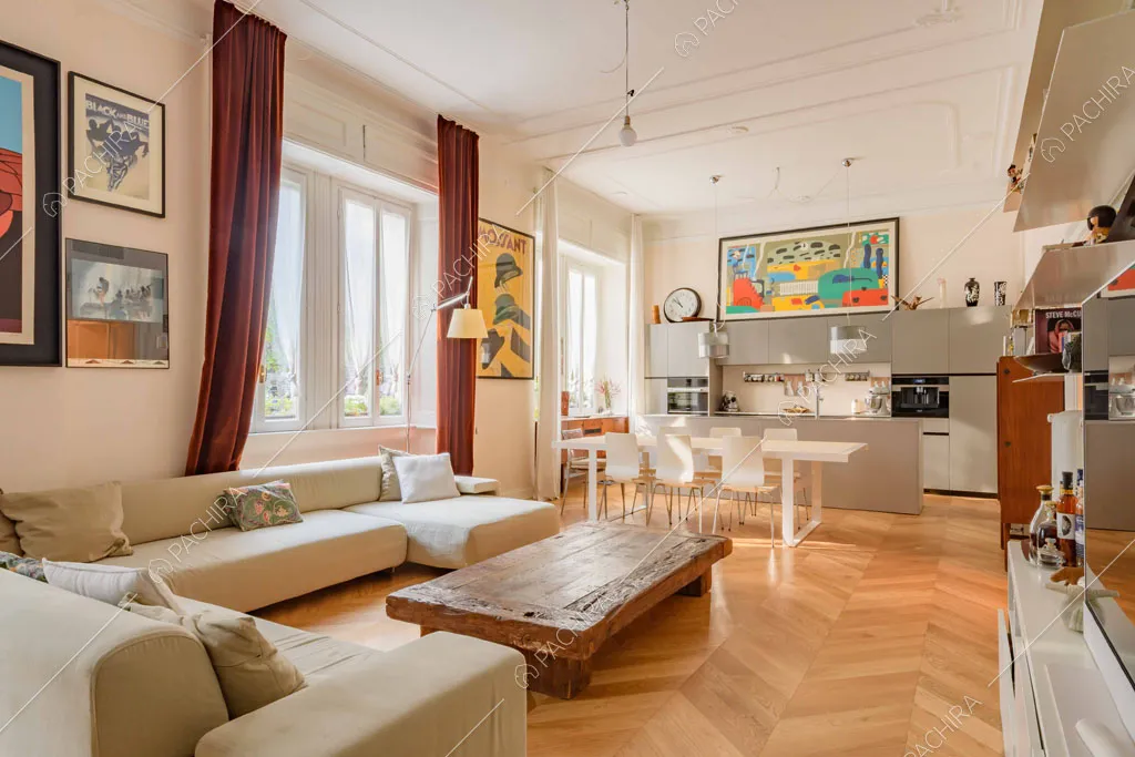 Grande divano angolare nella zona living con pavimento in parquet a spina di pesce