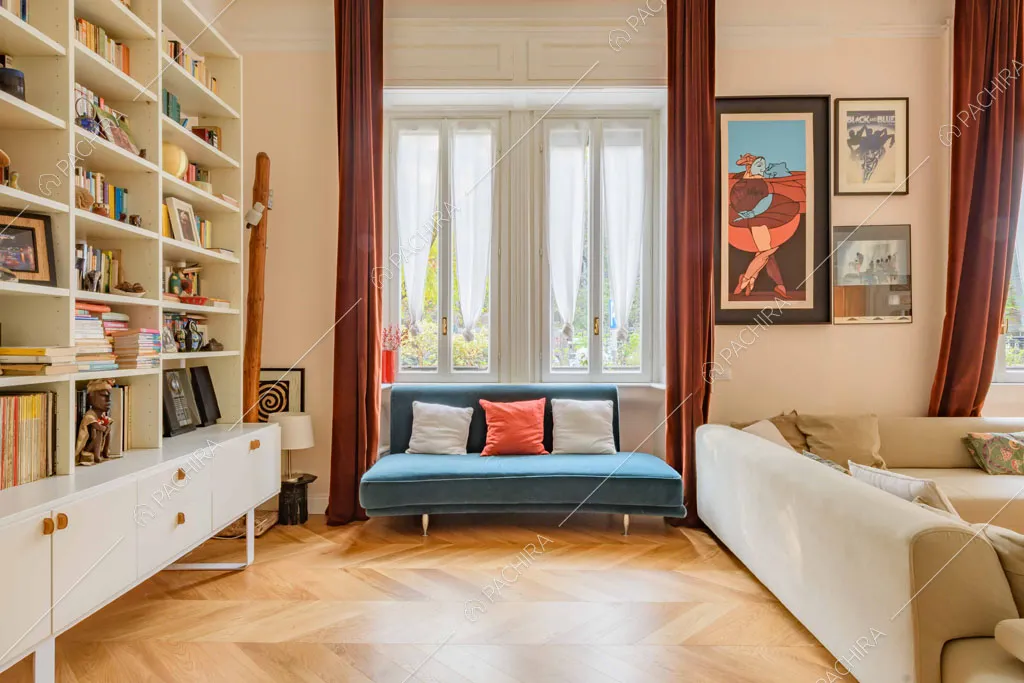 Divano di velluto blu e divano beige nella luminosa sala con libreria