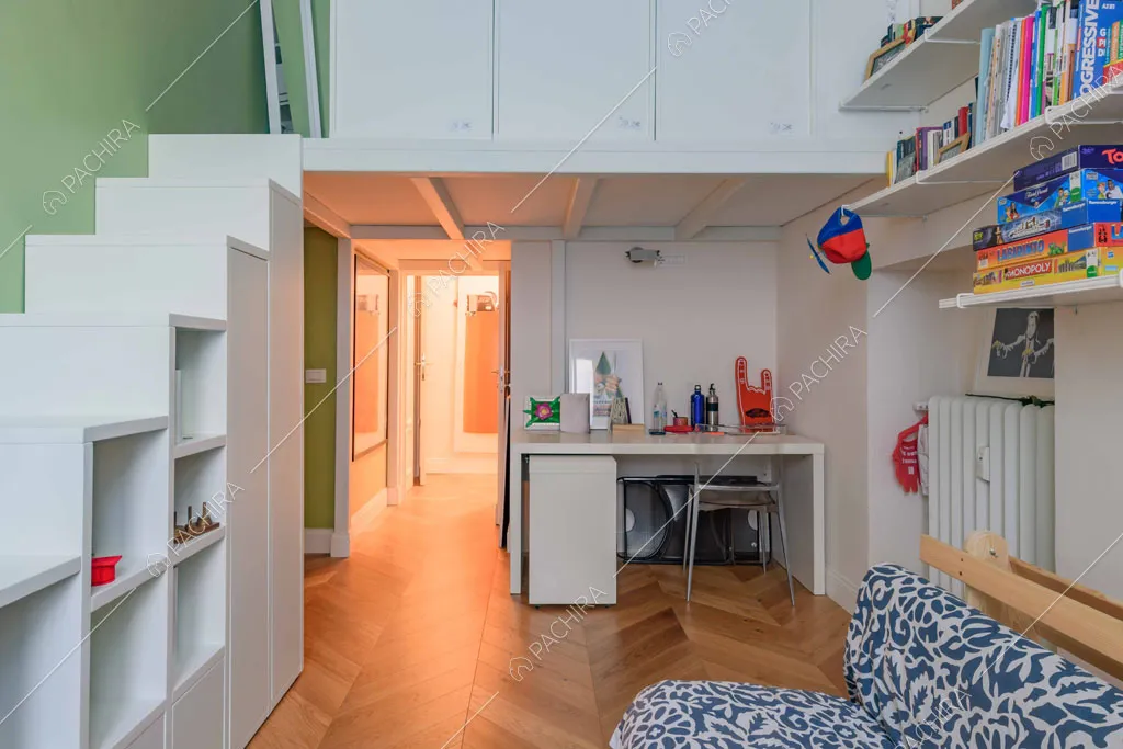 Camera da letto con soppalco, parete verde, scrivania e divano-letto