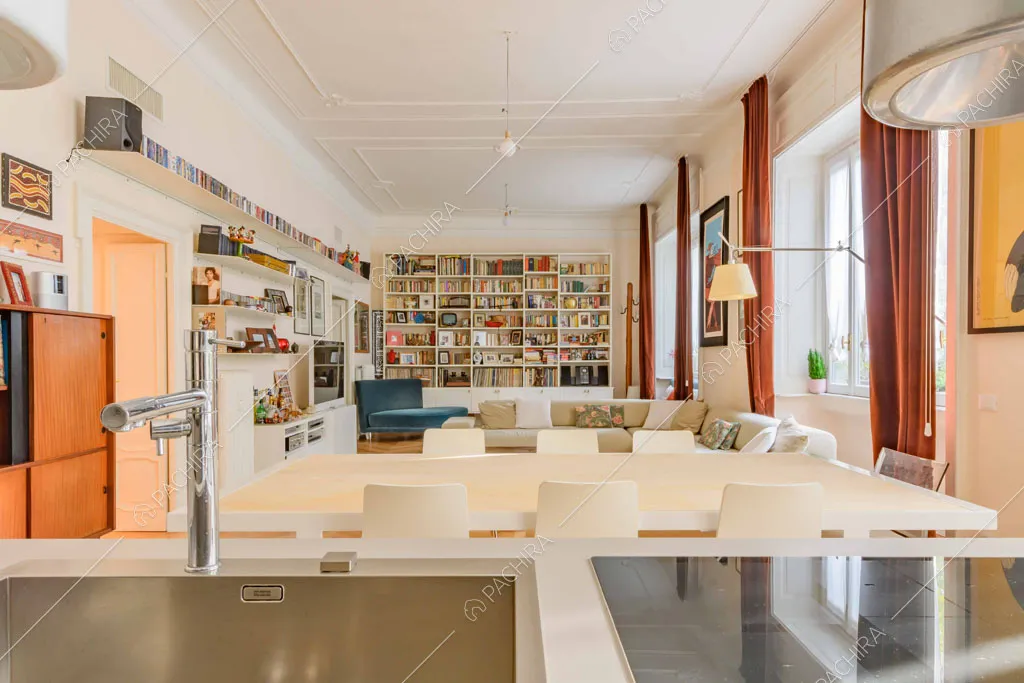 Dall'isola con fornelli a induzione vista sul tavolo da pranzo e sulla libreria
