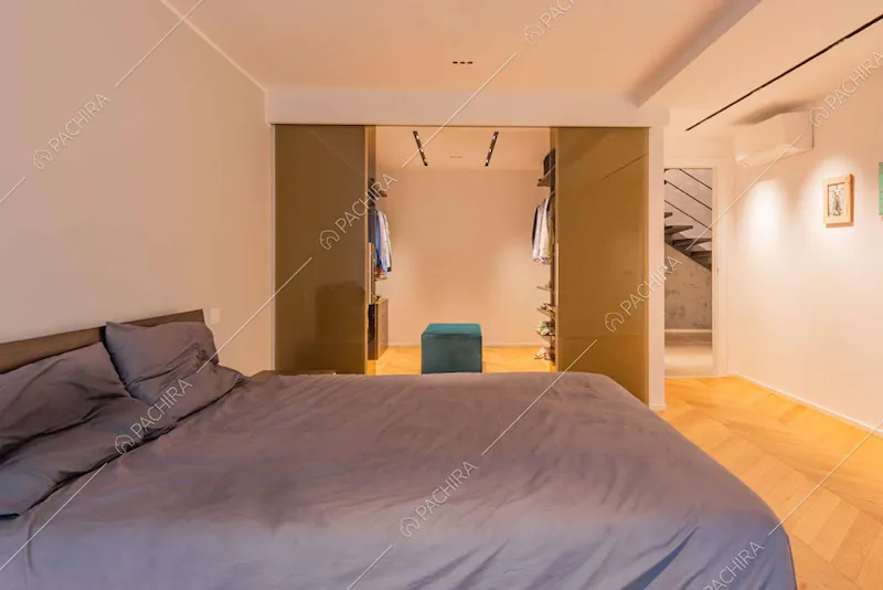 Letto matrimoniale nella camera con cabina armadio e pavimento in parquet
