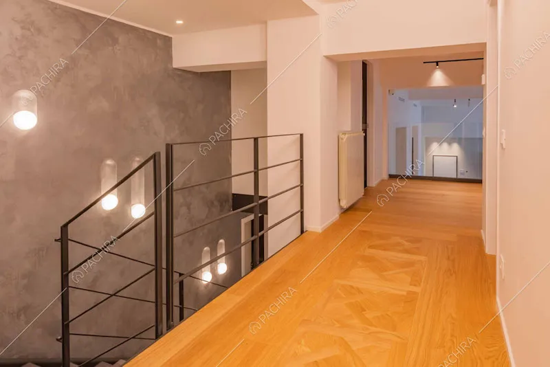 Pavimento in parquet del corridoio, scale in metallo e parete grigia