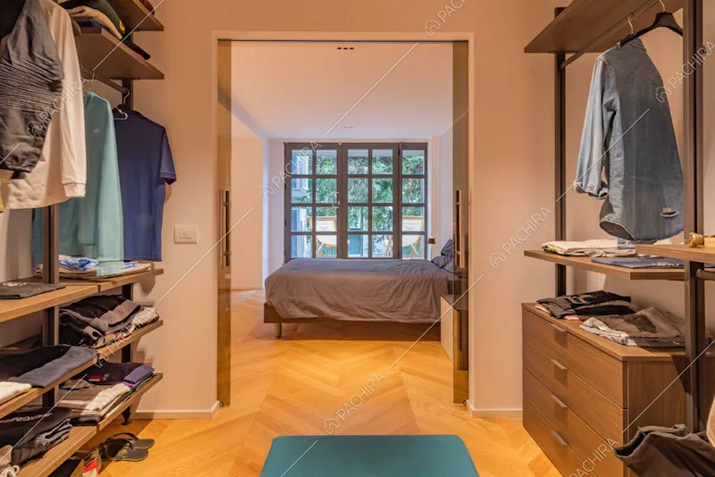 Dalla grande cabina armadio con pavimento in parquet vista sul letto matrimoniale