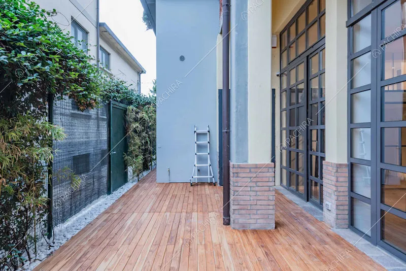 Giardino con vetrate, esterni gialli e in mattoni e pavimento in parquet da esterni