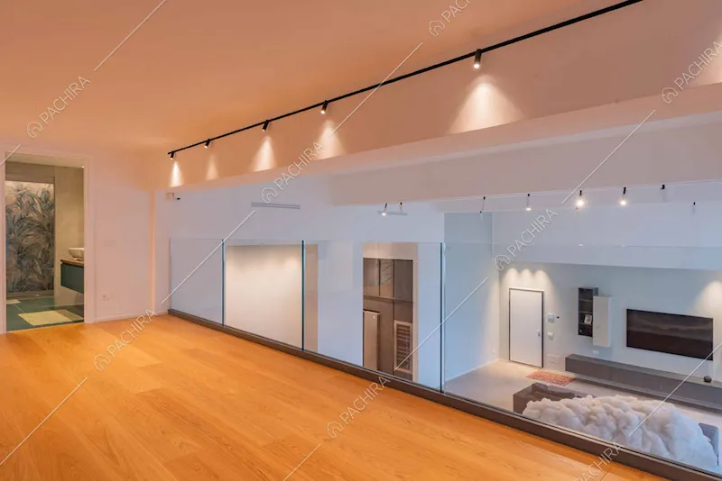Balconata con pavimento in parquet, parapetto in vetro e vista sul grande salone