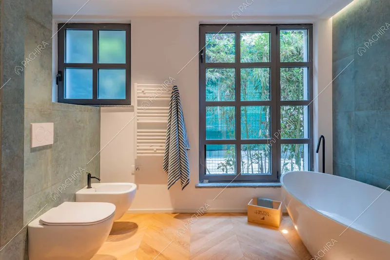 Pavimento in parquet a spina di pesce, vasca e piastrelle verderame nel bagno