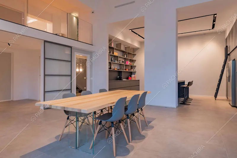 Tavolo da pranzo in legno, porta a vetri scorrevole e vista sulla cucina con isola