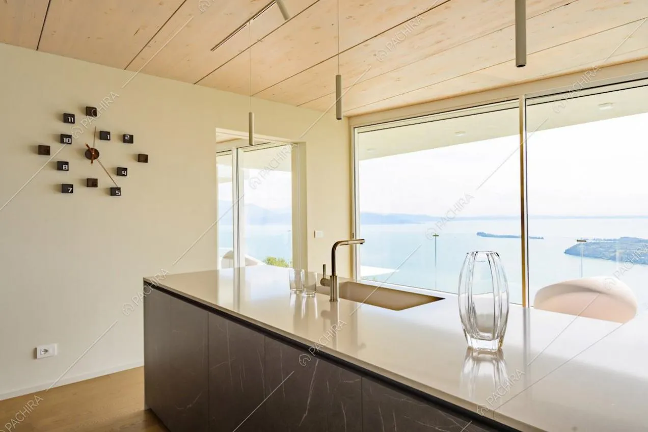Dalla cucina con pareti bianche vista sul lago tramite la grande porta-finestra