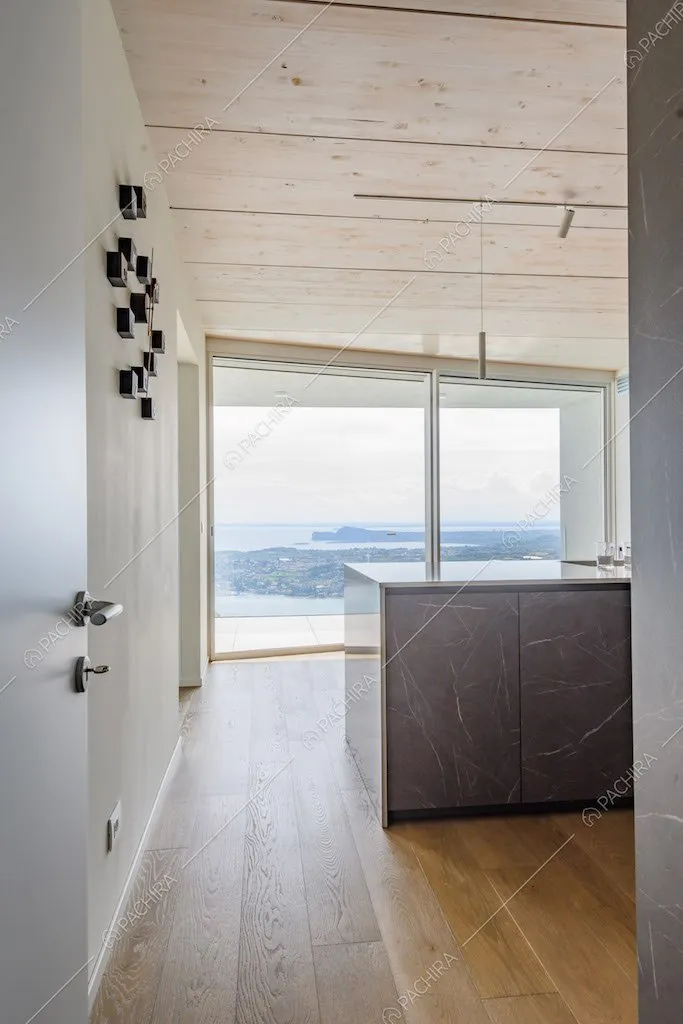 Cucina con pavimento in parquet e vista sul lago tramite le grandi vetrate